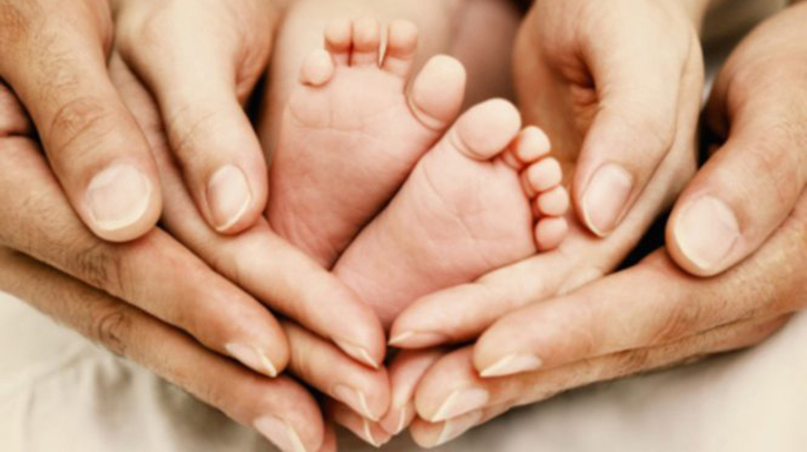 Manos de padre, madre y pies de bebé recién nacido para representar la baja de maternidad y paternidad